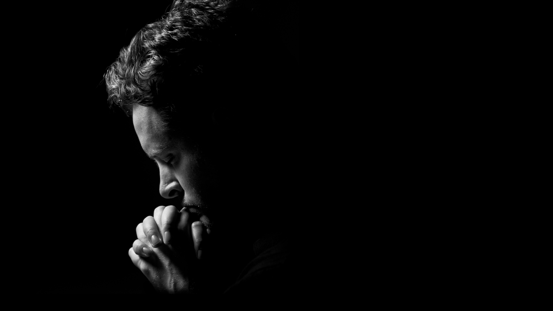 Mustavalkoinen valokuva, jossa mies rukoilee