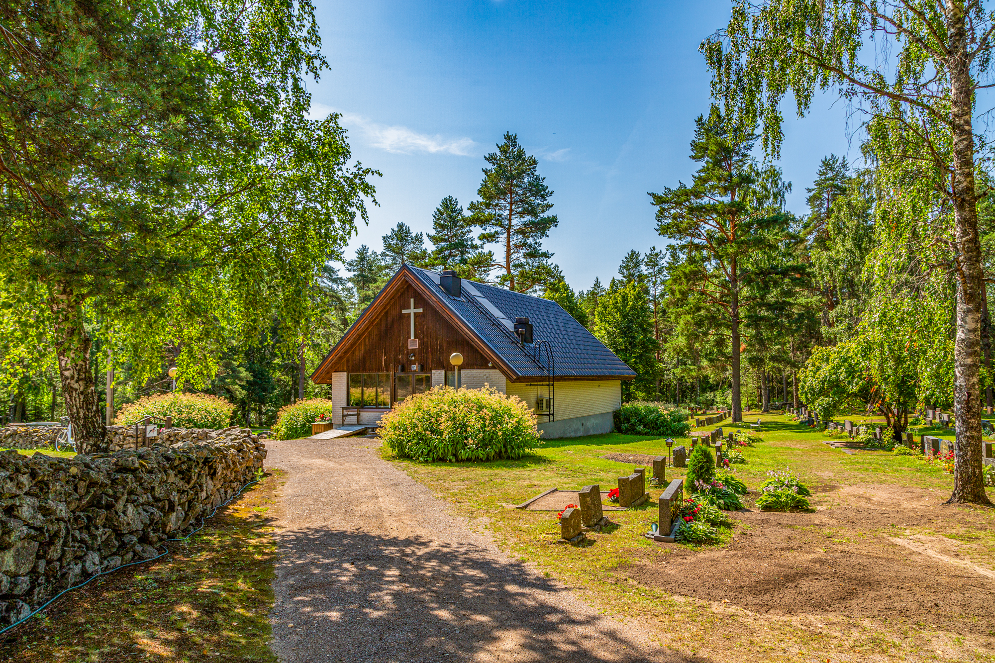 Ylämaan hautausmaa kesällä. Edessä kappeli ja vasemmalla vanha luonnonkiviaita.