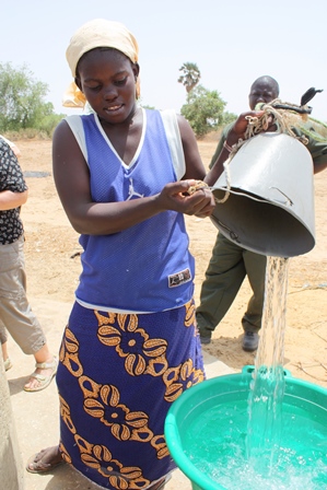 Afrikkalainen nainen vesiastioilla aurinkoisena päivänä.